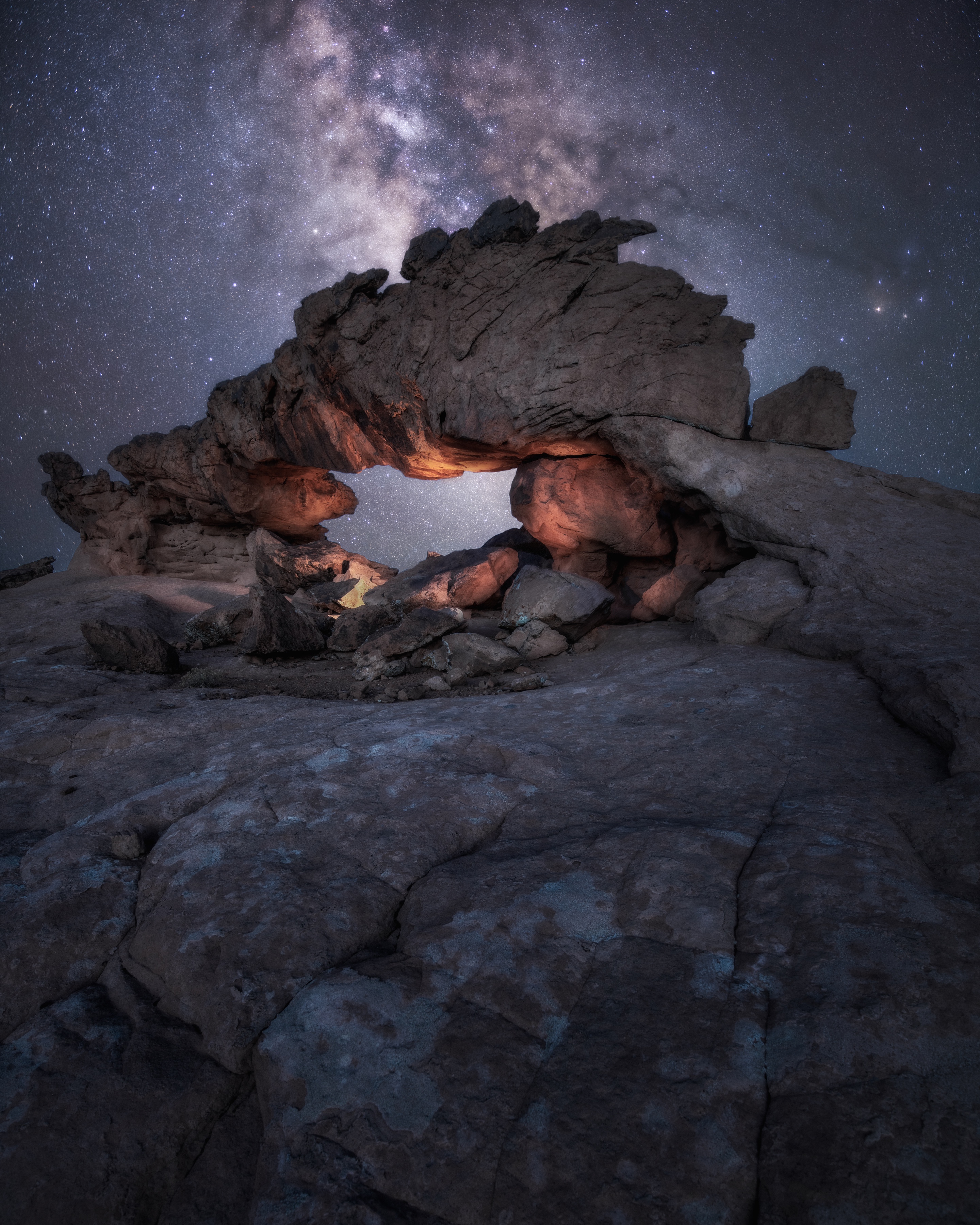 Creative composite of a Utah sandstone arch illuminated from within with the Milky Way core positioned through the opening.