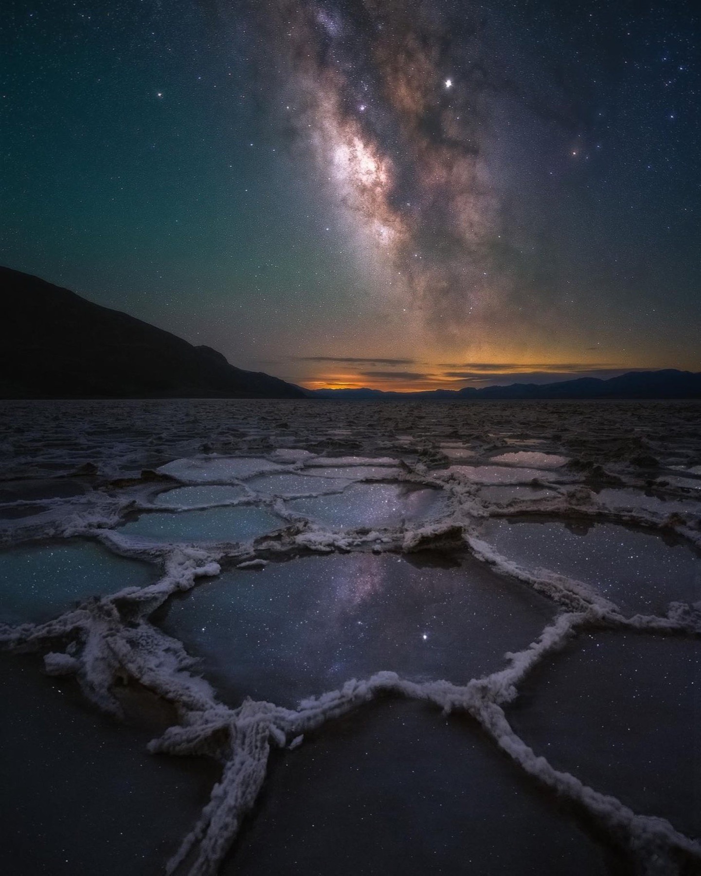 Milky Way galactic core reflected in polygonal salt pools at night